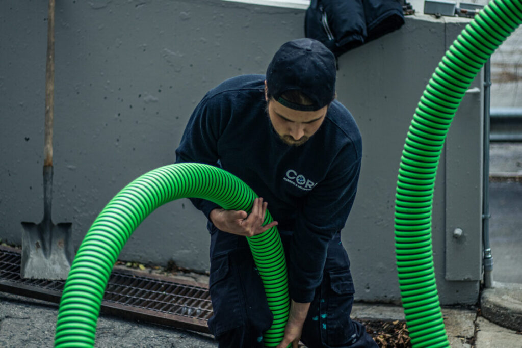 Core Plumbing employee using a vacuum to clean a trench drain, ensuring optimal drainage performance.